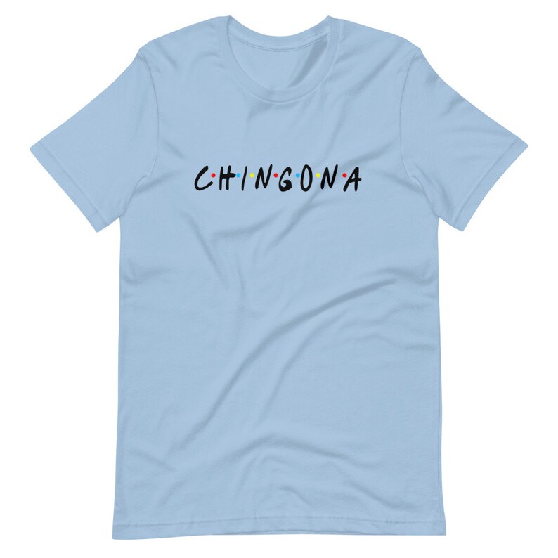 May include: Light blue t-shirt with the text "CHINGONA" in black with colorful dots between the letters.