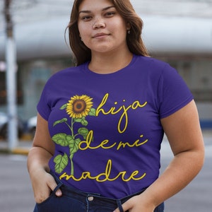 Puede incluir: Camiseta morada con un gr&aacute;fico de girasol y el texto "hija de mi madre" en amarillo.