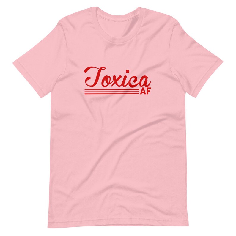 May include: Pink short-sleeved t-shirt with the text "Toxica AF" in red cursive lettering.