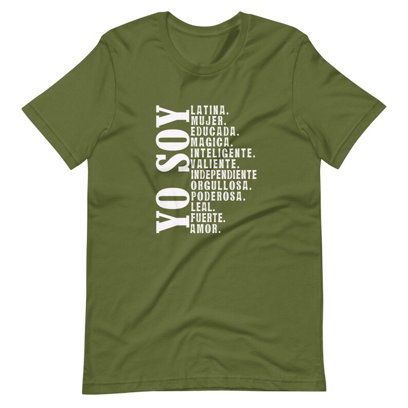 Puede incluir: Una camiseta verde con texto blanco que dice "YO SOY" y una lista de palabras en espa&ntilde;ol que describen a una mujer latina. Las palabras incluyen "Latina, Mujer, Educada, Magica, Inteligente, Valiente, Independiente, Orgullosa, Poderosa, Leal, Fuerte, Amor."