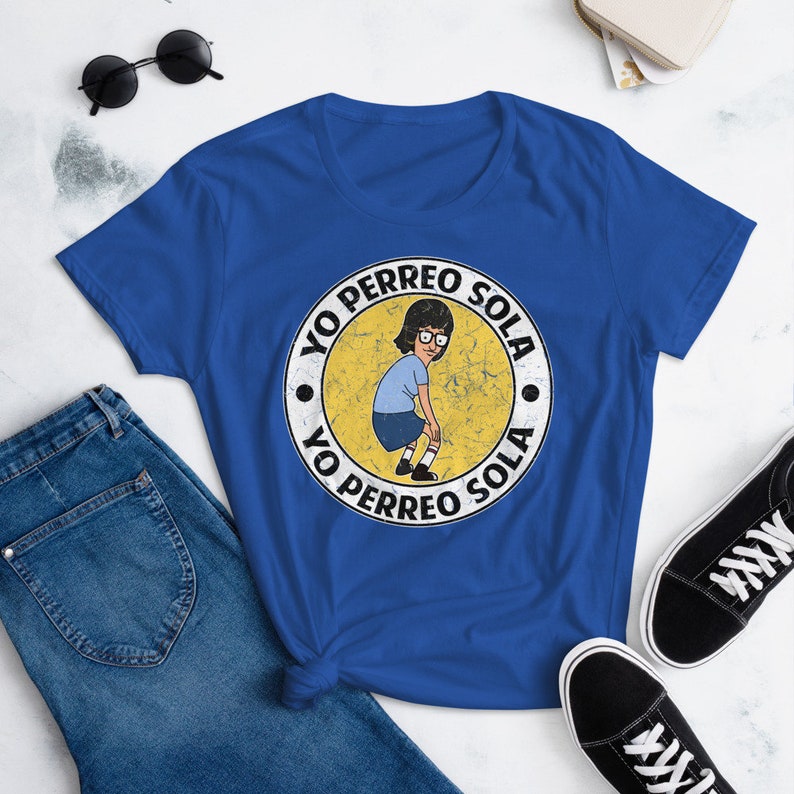 May include: A royal blue t-shirt with a yellow circle graphic featuring a cartoon woman dancing and the text "Yo Perreo Sola" repeated twice.