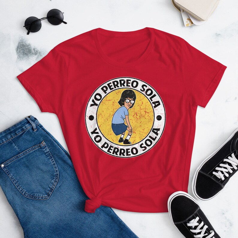 May include: Red t-shirt with a yellow circle graphic featuring a cartoon character dancing and the text "Yo Perreo Sola" repeated twice.