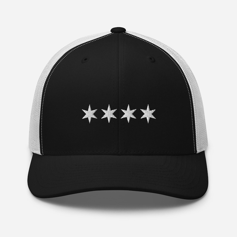May include: Black and white trucker hat with five white stars embroidered on the front. The hat has a black mesh back.