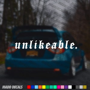 May include: A white vinyl decal with the word "unlikeable." in a gothic font is displayed on the rear window of a blue car. The decal is from Madd Decals.