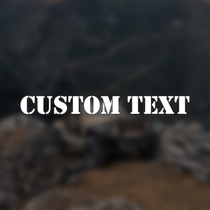 May include: White "CUSTOM TEXT" stencil-style lettering against a blurred, dark background. The text is centered and bold, with a military-inspired font. The background features a landscape with muted tones.