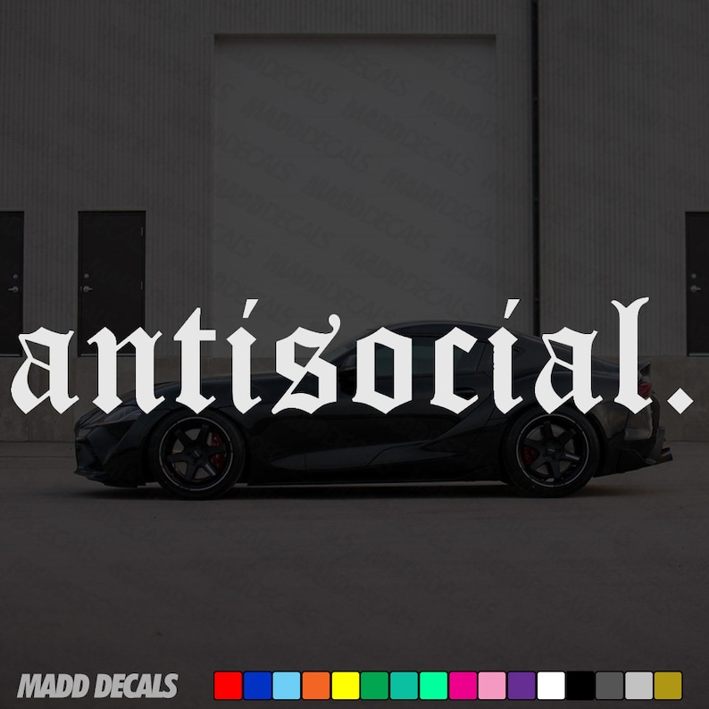 May include: White "antisocial." decal in gothic font, displayed above a black sports car. The car is parked on a dark surface, with a building in the background. The decal is from MADD DECALS.