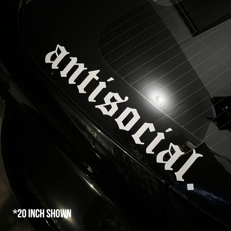 May include: White vinyl decal with the word "antisocial" in a gothic font, affixed to the black surface of a car. The text is approximately 20 inches long. The decal is designed for vehicle customization.