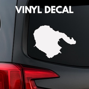 Peut inclure: Autocollant en vinyle blanc représentant une forme de masse terrestre, possiblement un littoral ou une île, sur fond noir. Le texte "VINYL DECAL" est au-dessus de la forme en lettres blanches. L'autocollant est collé sur une vitre de véhicule.