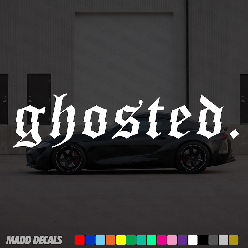 以下が含まれることがあります： 上部に白いゴシック体で「ghosted」という文字が書かれた黒いスポーツカー。車は黒いリムと赤いブレーキキャリパーを備えています。画像の下部には「MADD DECALS」というテキストとカラーパレットがあります。