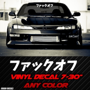 Peut inclure: Voiture de sport noire avec un autocollant blanc sur le pare-brise. L'autocollant présente des caractères japonais. En dessous de la voiture, le texte "VINYL DECAL 7-30" ANY COLOR" est affiché en rouge. La voiture est garée sur une surface grise.