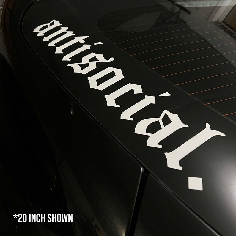 May include: A black car with a white decal that reads "antisocial" in a gothic font. The decal is approximately 20 inches long and is affixed to the rear window of the vehicle.