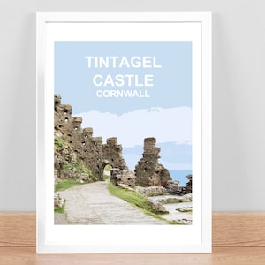 May include: A vintage travel poster featuring a photo of Tintagel Castle in Cornwall, England. The poster has a light blue background with white text that reads "Tintagel Castle Cornwall".
