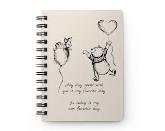 May include: A Winnie the Pooh and Piglet themed notebook with a spiral binding. The cover features a black and white illustration of Winnie the Pooh and Piglet holding heart-shaped balloons. The text on the cover reads "Any day spent with you is my favourite day. So today is my new favourite day."