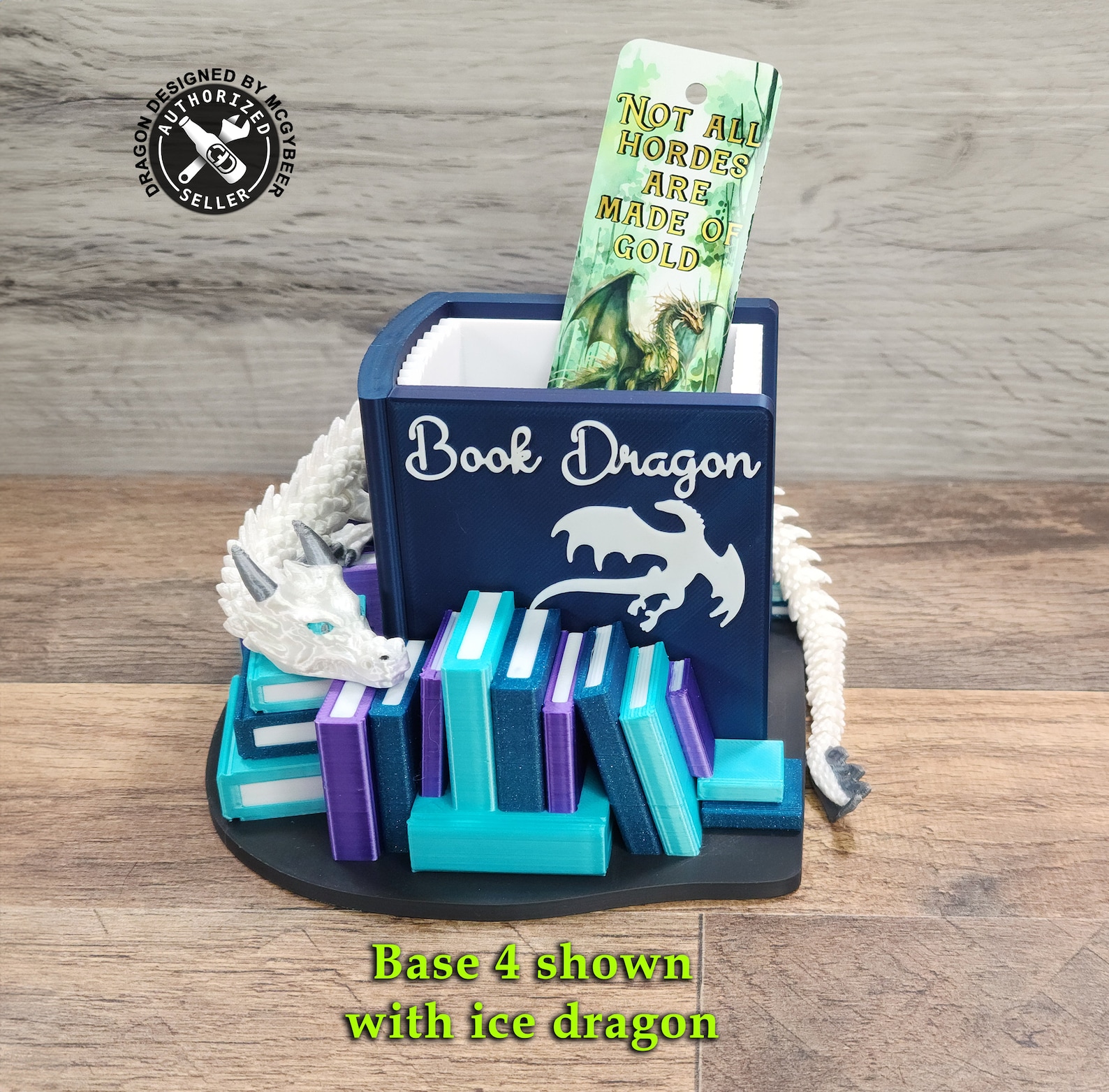A pen holder shaped like a dark blue book that says "Book Dragon" on it with a design of a dragon. It is surrounded by smaller teal, blue, and purple books and has a white dragon wrapped around it.