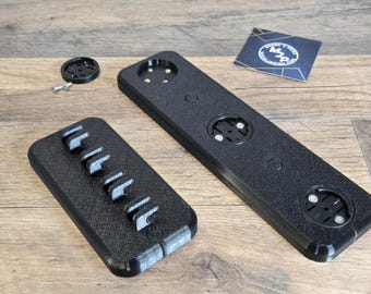 May include: Three black 3D printed mounts for bike accessories. One mount has five slots for holding tools, another has three circular openings for attaching bike computers, and the third has four circular openings for attaching bike lights.