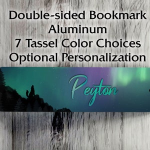 May include: Double-sided aluminum bookmark with a design featuring a wolf silhouette on a mountain under the aurora borealis. The name "Peyton" is written in a teal script. Includes text: "7 Tassel Color Choices Optional Personalization."
