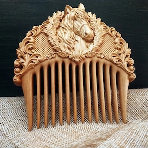 May include: A wooden comb with a carved horse head design. The comb is made of light brown wood and has a detailed, intricate design.