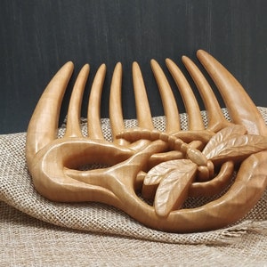 Puede incluir: Un peine de madera para el cabello con un dise&ntilde;o de lib&eacute;lula tallado. El peine es de color marr&oacute;n claro y tiene un acabado liso y pulido.