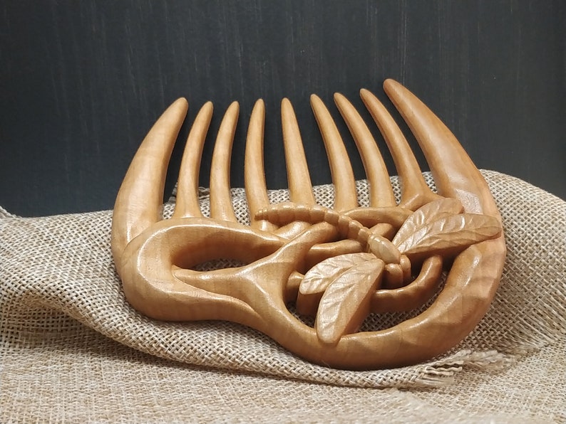 Puede incluir: Un peine de madera para el cabello con un dise&ntilde;o de lib&eacute;lula tallado. El peine es de color marr&oacute;n claro y tiene un acabado liso y pulido.
