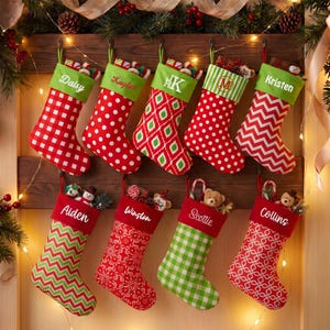 May include: Eight Christmas stockings hanging in two rows, each featuring a green cuff with a personalized name or monogram. The stockings display various patterns including red and white gingham, polka dots, chevron, and floral designs.