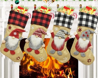 May include: Four Christmas stockings made of tan burlap with buffalo plaid cuffs in red and black or white and black. Each stocking features a plush gnome with a long white beard, a patterned hat, and small snowflake accents on the fabric.