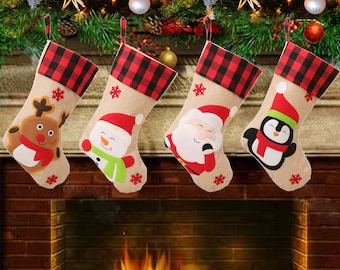 May include: Four Christmas stockings with different festive characters. The stockings are made of burlap with a red and black plaid cuff. The characters are a reindeer, a snowman, Santa Claus, and a penguin.