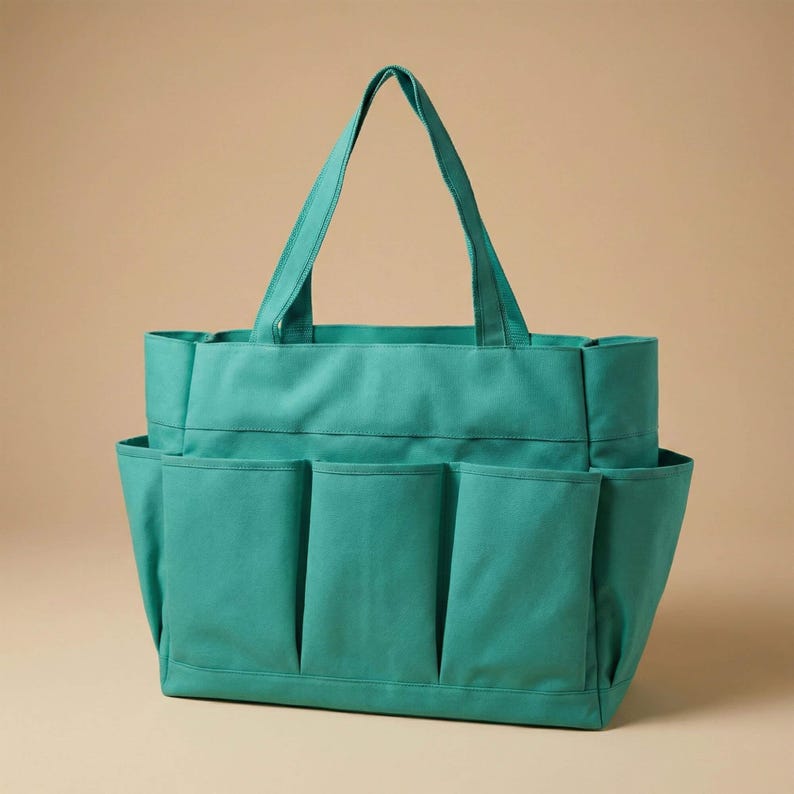 May include: A teal canvas tote bag with multiple exterior pockets. The bag has a rectangular shape with a wide opening and two handles for carrying. The pockets are vertically oriented and provide additional storage space.