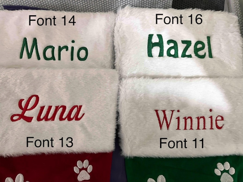 May include: Four personalized Christmas stockings with white faux fur tops. The names "Mario" in green, "Hazel" in green, "Luna" in red, and "Winnie" in red are embroidered on the stockings. The bottom sections are red and green with paw print designs.