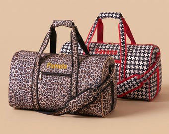 May include: Two duffel bags with zippers and adjustable straps. The front bag features a brown and black leopard print with the name Pamela embroidered in yellow. The back bag has a black and white houndstooth pattern with red trim and the name Savana embroidered in red.