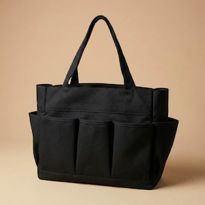 May include: Black tote bag with multiple exterior pockets and two sturdy handles. The bag is made of a durable fabric and features a rectangular shape with a flat bottom. The pockets are evenly spaced along the sides.