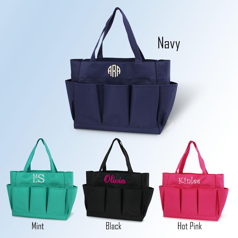 May include: Navy blue tote bag with multiple exterior pockets and a monogram. Additional bags in mint green, black, and hot pink are displayed, each with personalized text. The bags have sturdy handles and are designed for carrying items.