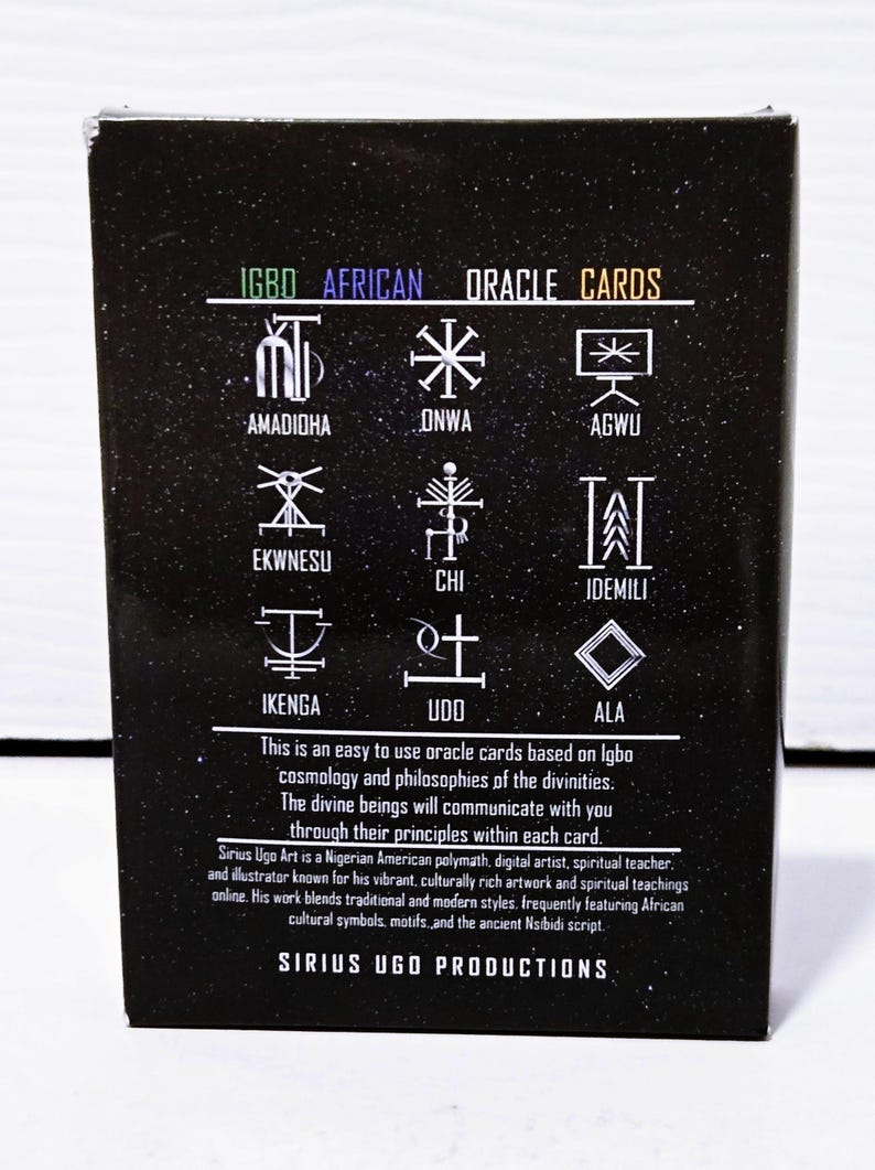 May include: Black box of Igbo African Oracle Cards. The box features white symbols and text, including "IGBO AFRICAN ORACLE CARDS" and the Sirius Ugo Productions logo. The text describes the cards' purpose and the artist's background.