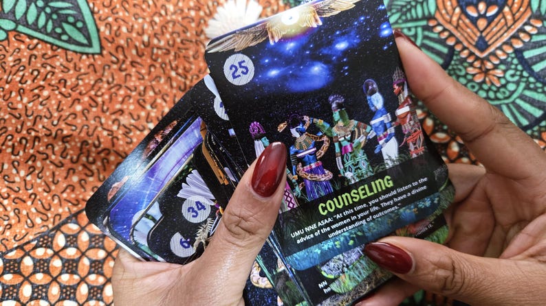 May include: A deck of oracle cards with a black background and images of figures in colorful clothing. The card in focus has the word "COUNSELING" and the number "25". The cards are held in a person's hand.
