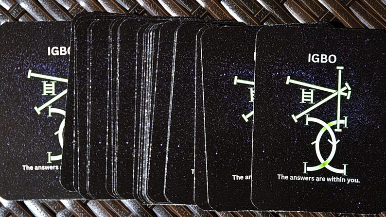May include: A deck of black cards with a starry background. Each card features the word "IGBO" and a geometric design in white and green. The text "The answers are within you" is printed on the bottom of the cards.