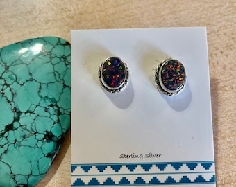 May include: A pair of sterling silver earrings with oval-shaped black opal stones. The earrings are on a white card with the text "Sterling Silver".