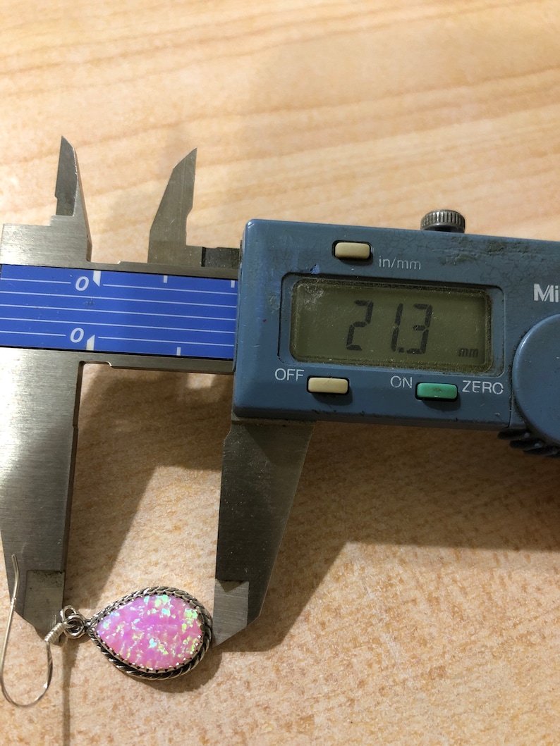 May include: A pink opal earring with a silver setting, measured at 2.13 mm using a digital caliper.