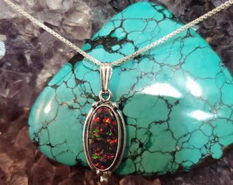 May include: A silver chain necklace with a pendant featuring a dark iridescent oval opal stone set in a silver bezel.