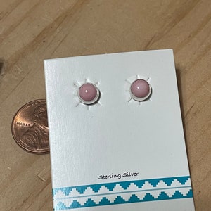 May include: A pair of pink gemstone earrings with sterling silver settings. The earrings are displayed on a white card with the text "Sterling Silver" printed on it.