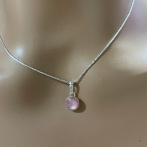May include: A silver chain necklace with a pink gemstone pendant.