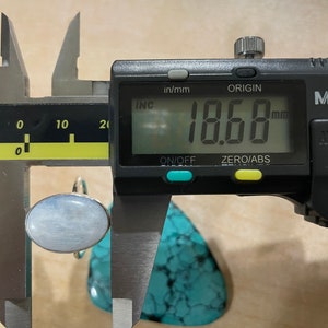 Puede incluir: Un anillo de plata con una piedra ovalada azul claro, medido a 18,68 mm, usando un calibre digital.