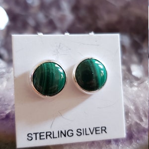 May include: A pair of sterling silver earrings with green malachite stones. The earrings are on a white card with the text "STERLING SILVER".