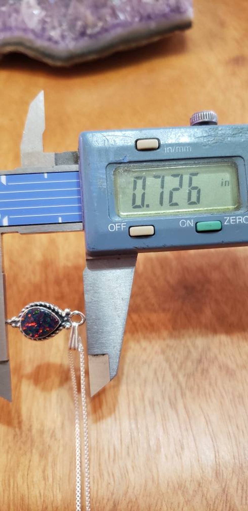 May include: A black opal pendant with a silver chain. The opal is a teardrop shape and measures 0.726 inches in length.