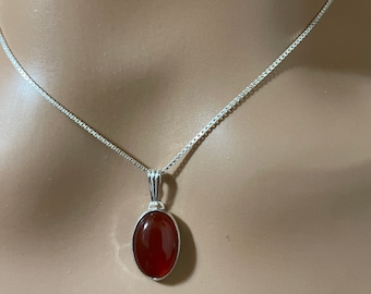 May include: A silver chain necklace with a red carnelian oval pendant.
