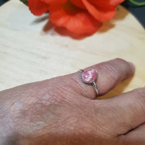 Puede incluir: Un anillo de plata con una piedra preciosa en forma de l&aacute;grima rosa y blanca.