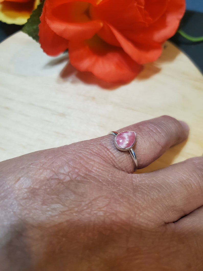 Puede incluir: Un anillo de plata con una piedra preciosa en forma de l&aacute;grima rosa y blanca.