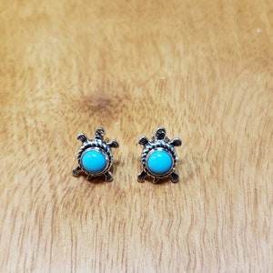 May include: A pair of silver turtle earrings with turquoise stones.
