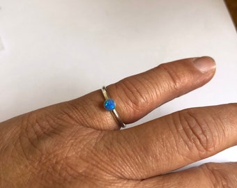 May include: A silver ring with a small blue opal gemstone.