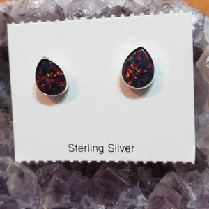 Puede incluir: Un par de pendientes de plata de ley con piedras de ópalo en forma de lágrima. Los ópalos son una mezcla de negro, rojo y verde.