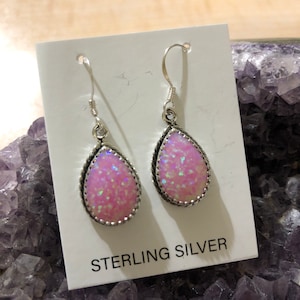 May include: A pair of sterling silver earrings with pink opal teardrop stones. The earrings have a delicate, feminine design and are perfect for everyday wear.