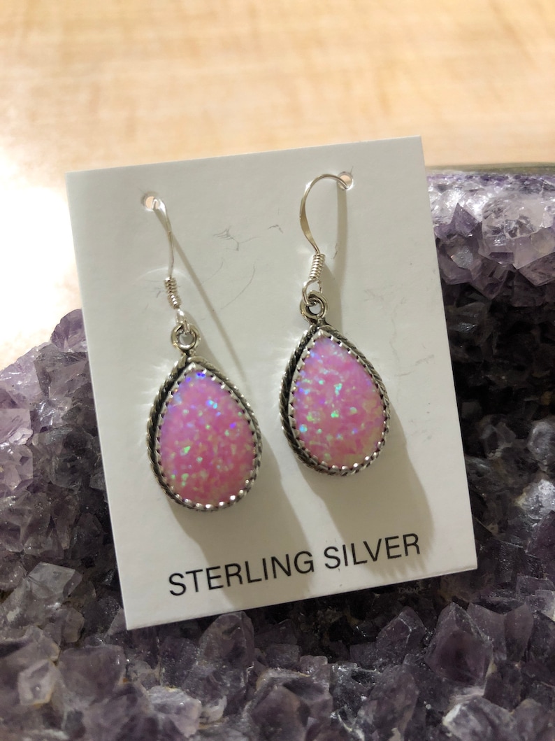 May include: A pair of sterling silver earrings with pink opal teardrop stones. The earrings have a delicate, feminine design and are perfect for everyday wear.